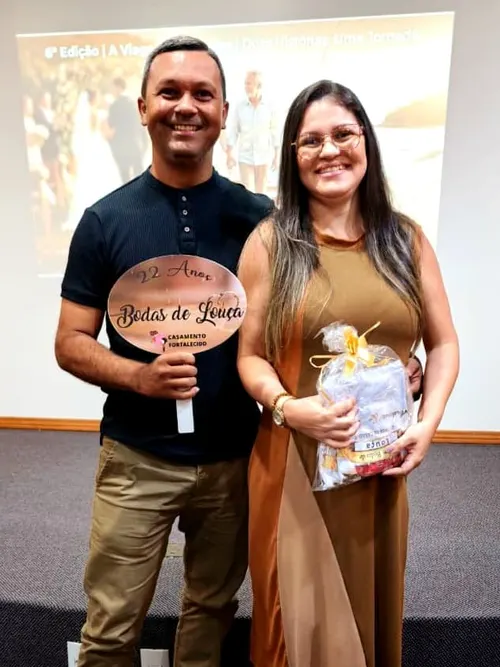 Casal da Viagem das Bodas segurando a plaquinha de 22 anos de casados, Bodas de Louça