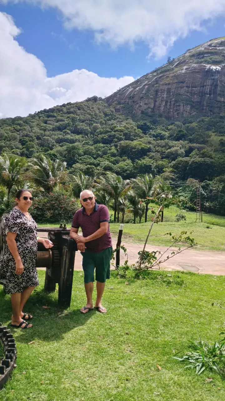 Casal de clientes passeando num gramado com uma serra ao fundo